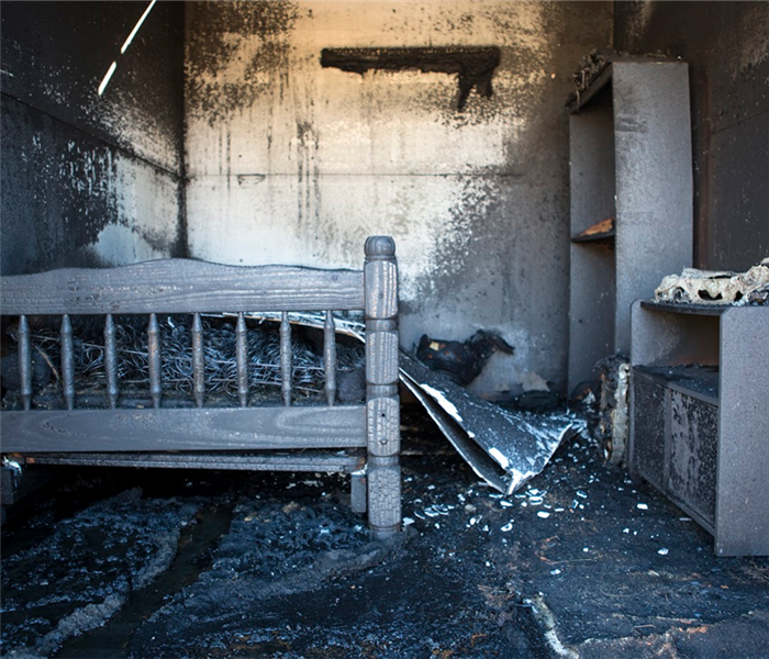 a fire damaged bedroom with soot covering the furniture and floors