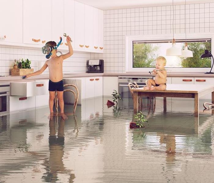 Two kids playing in standing water in a kitchen. 