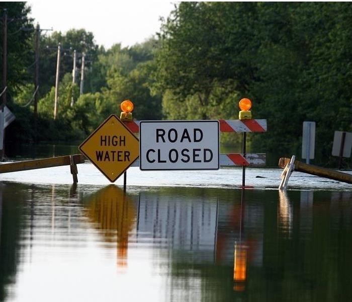 flooded road; 'high water' and 'road closed' signage visible